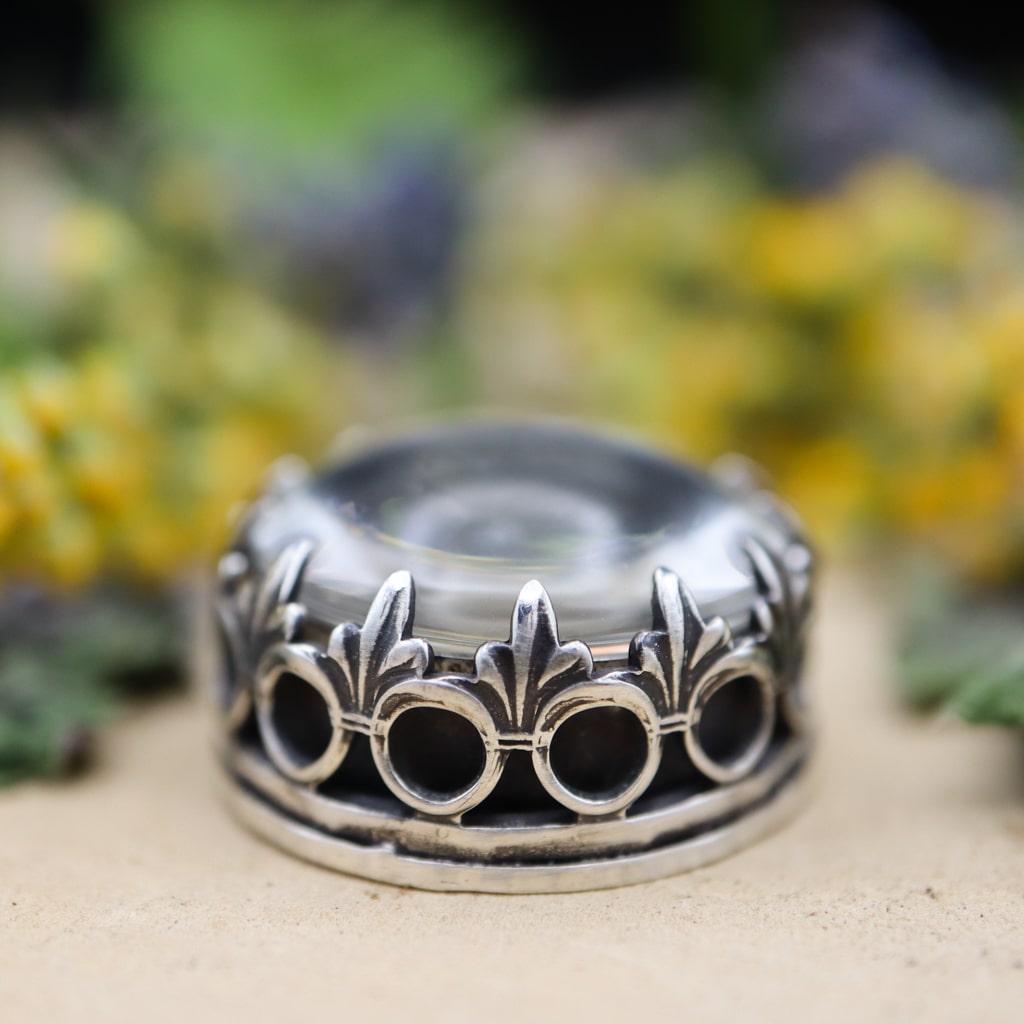 A close up photo of the side of the pendant showing the intricate bezel that is holding the clear quartz stone down on the top.