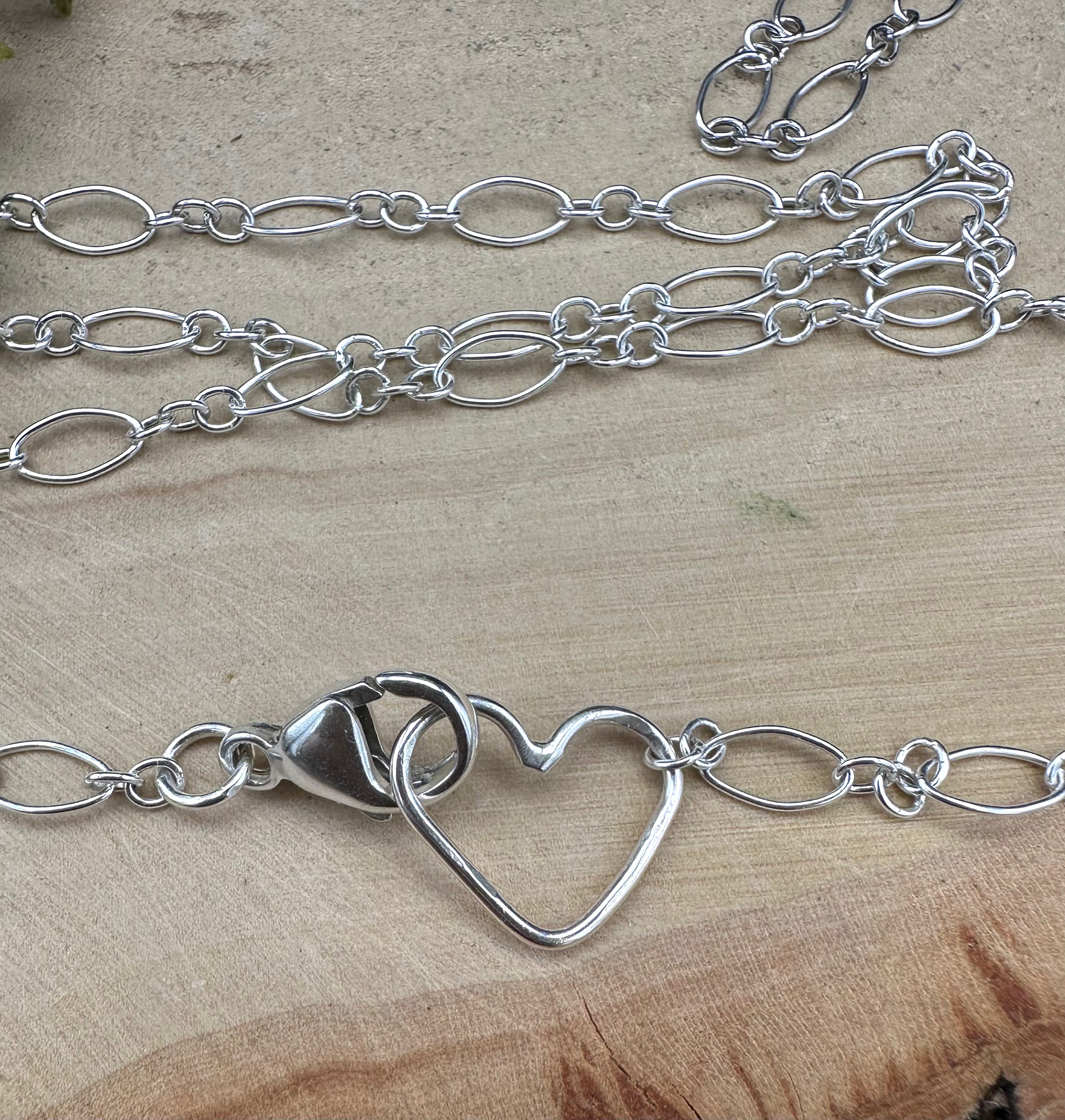A close up photo of the sterling silver loop chain and the clasp with heart shaped necklace end.