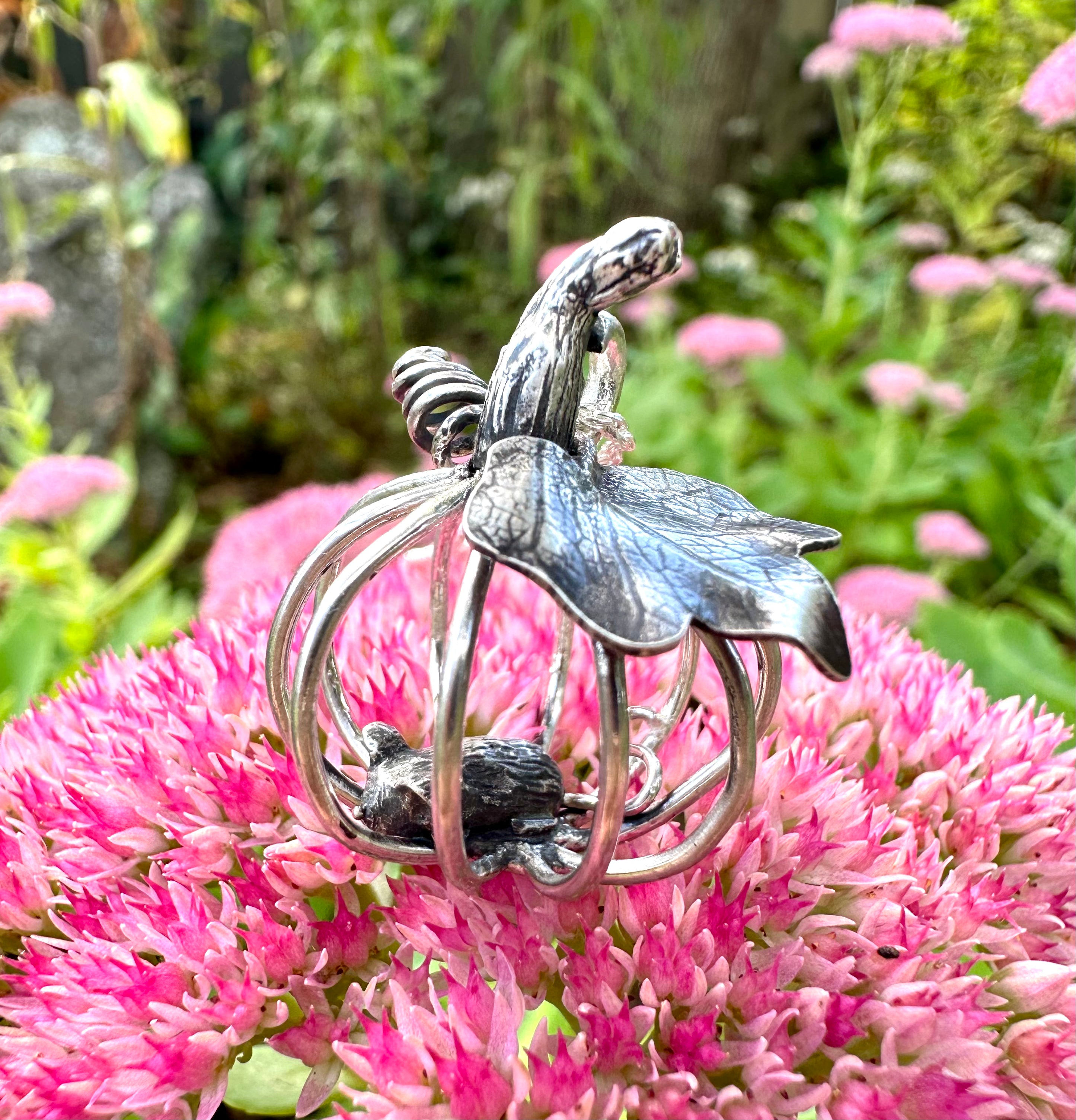 Silver pumpkin and mouse pendant on pink flowers with a natural background