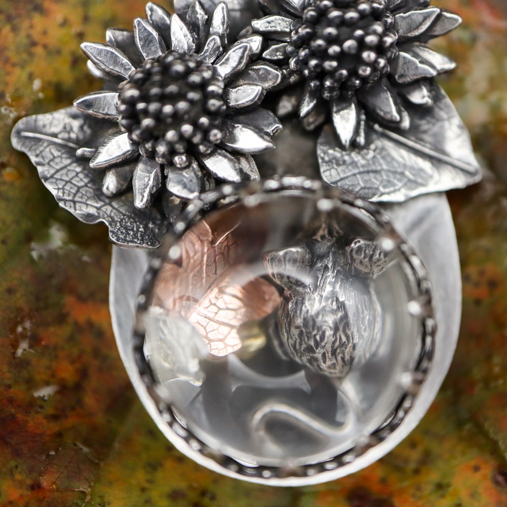 A close up of the bottom of the pendant where the tiny mouse and the leaves are held.