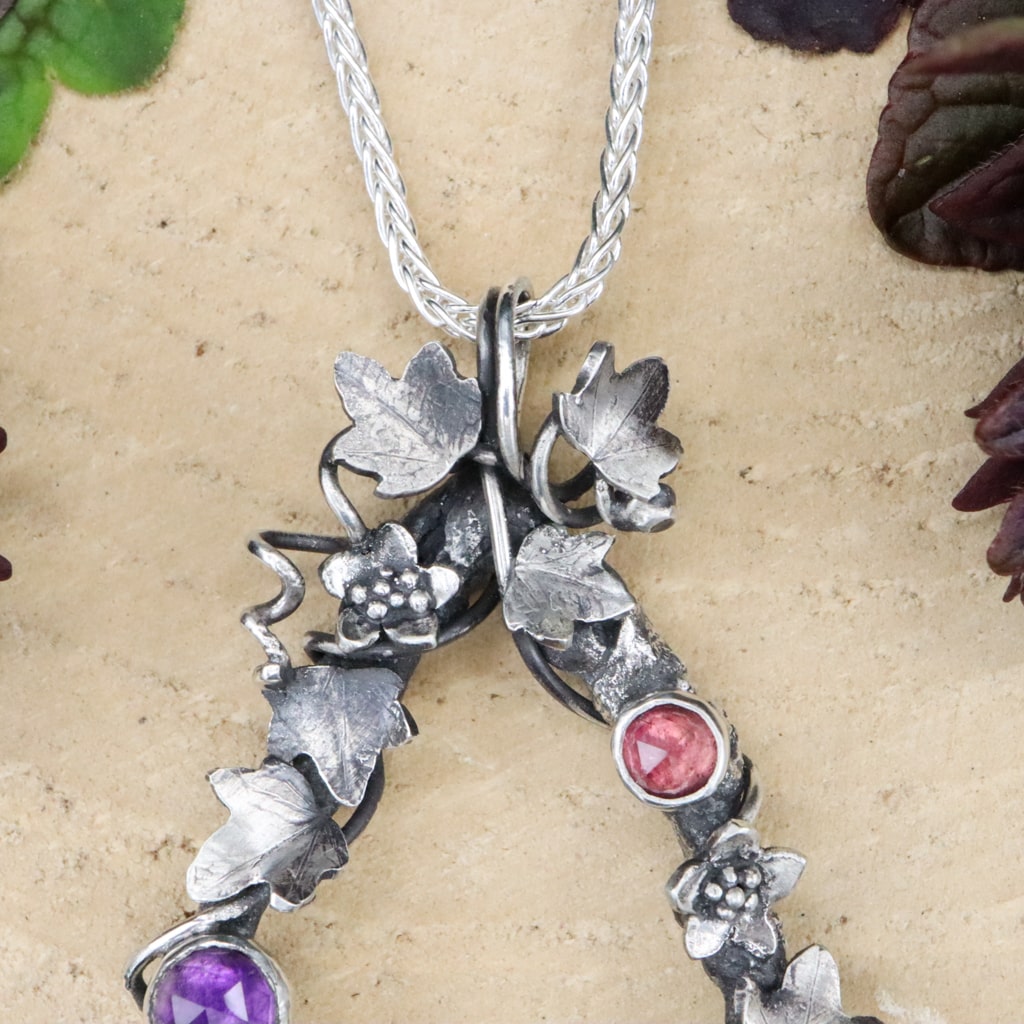 At the top of the necklace there is a cluster of ivy vines and leaves.