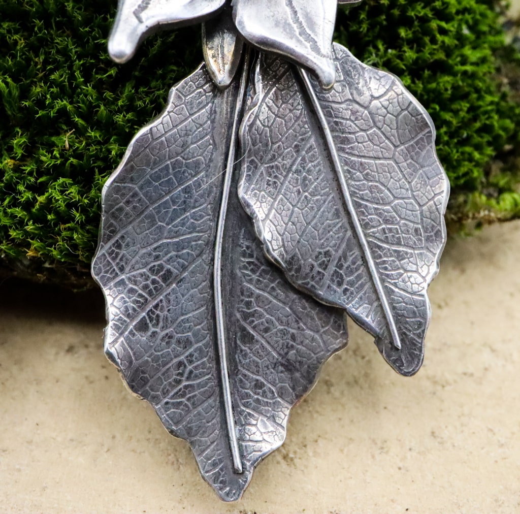 A close up photo of the sterling silver leaves that dangle below the borage flowers.