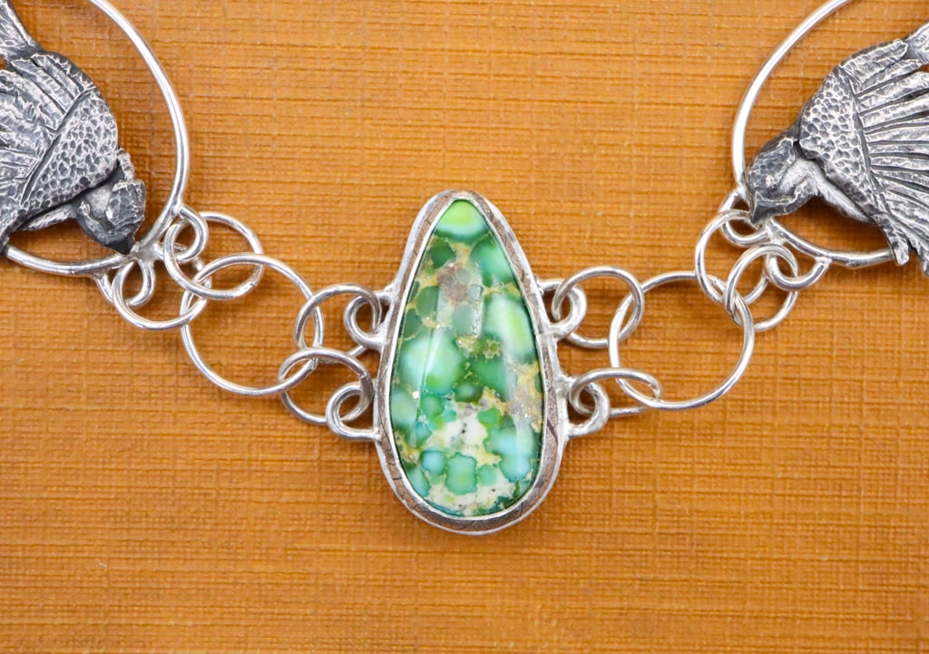 A pear shaped green spotted Sonoran Mountain turquoise stone is in the center of the chickadee bracelet. 