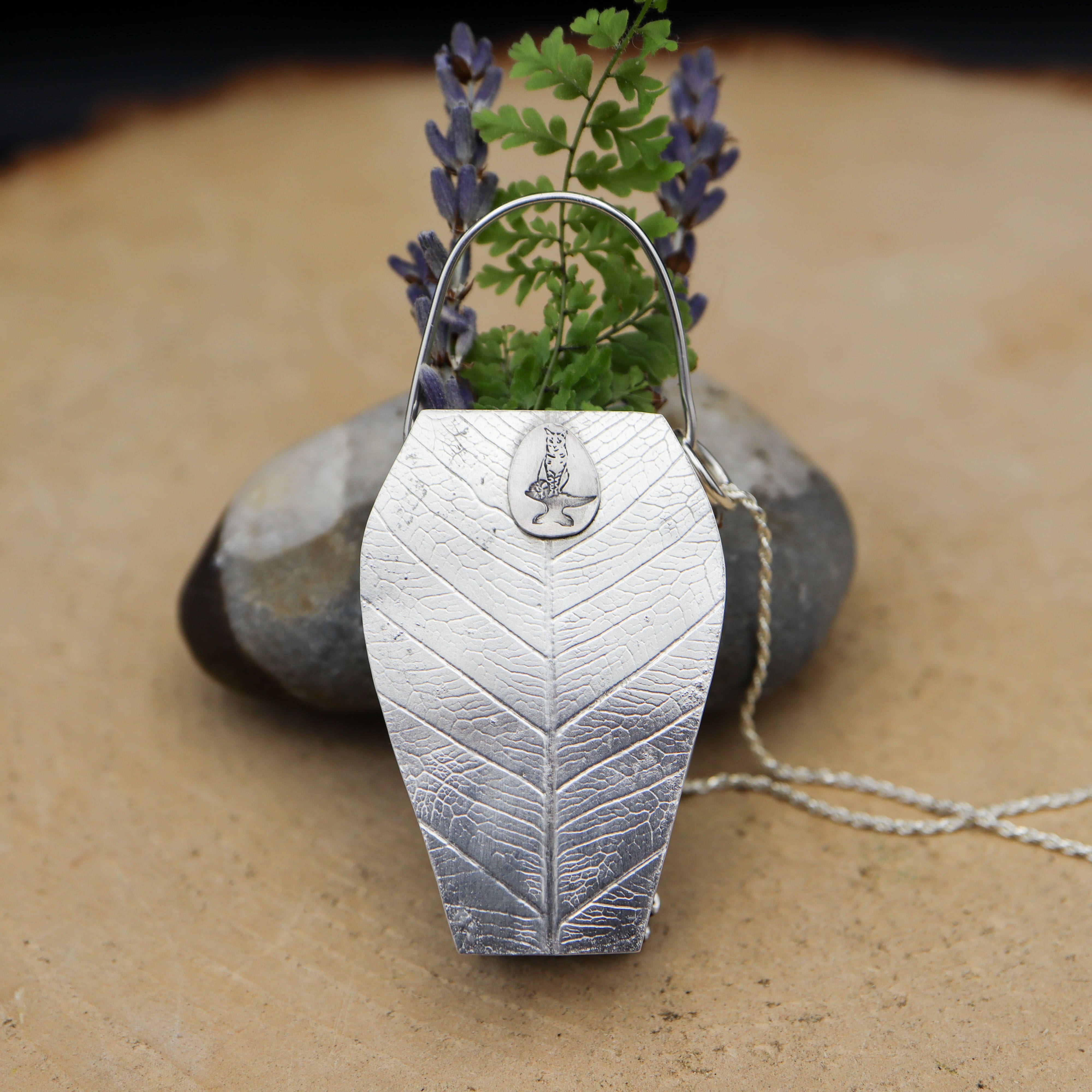 The back of the sterling silver coneflower vase necklace showing the leaf pattern and maker's mark.