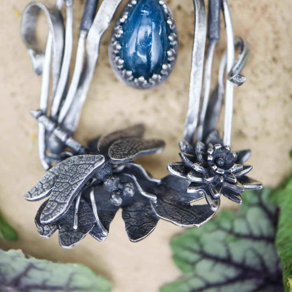A close up pf the hand carved dragonfly next to the water lily flower.