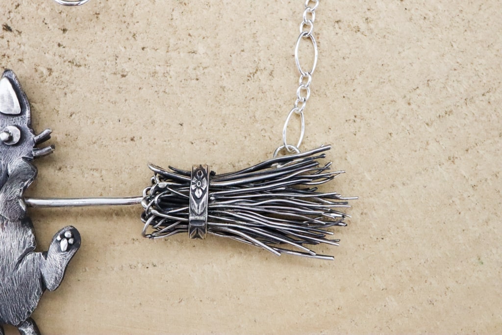 A close up of the sterling silver witches broom with floral details.