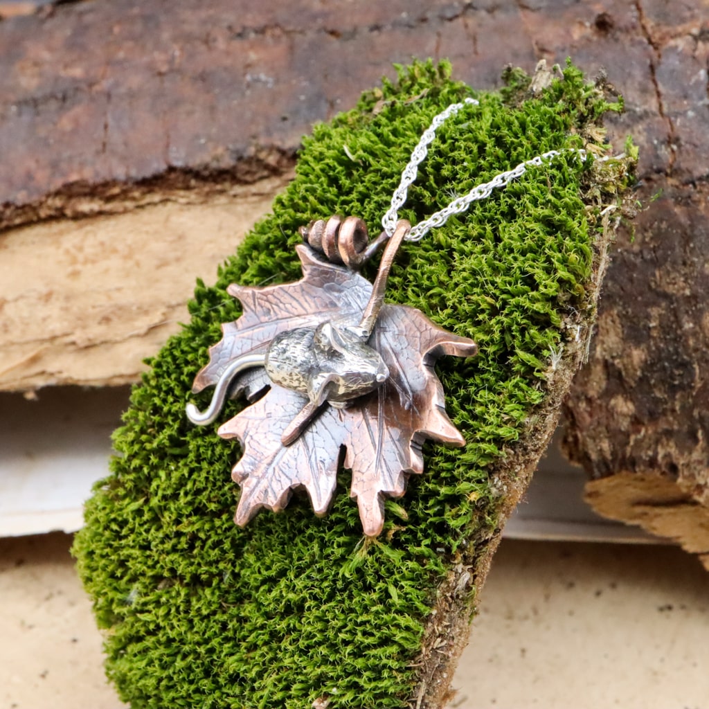 The angle of this photo shows you a little more of the face of the sterling silver mouse on a maple leaf necklace.