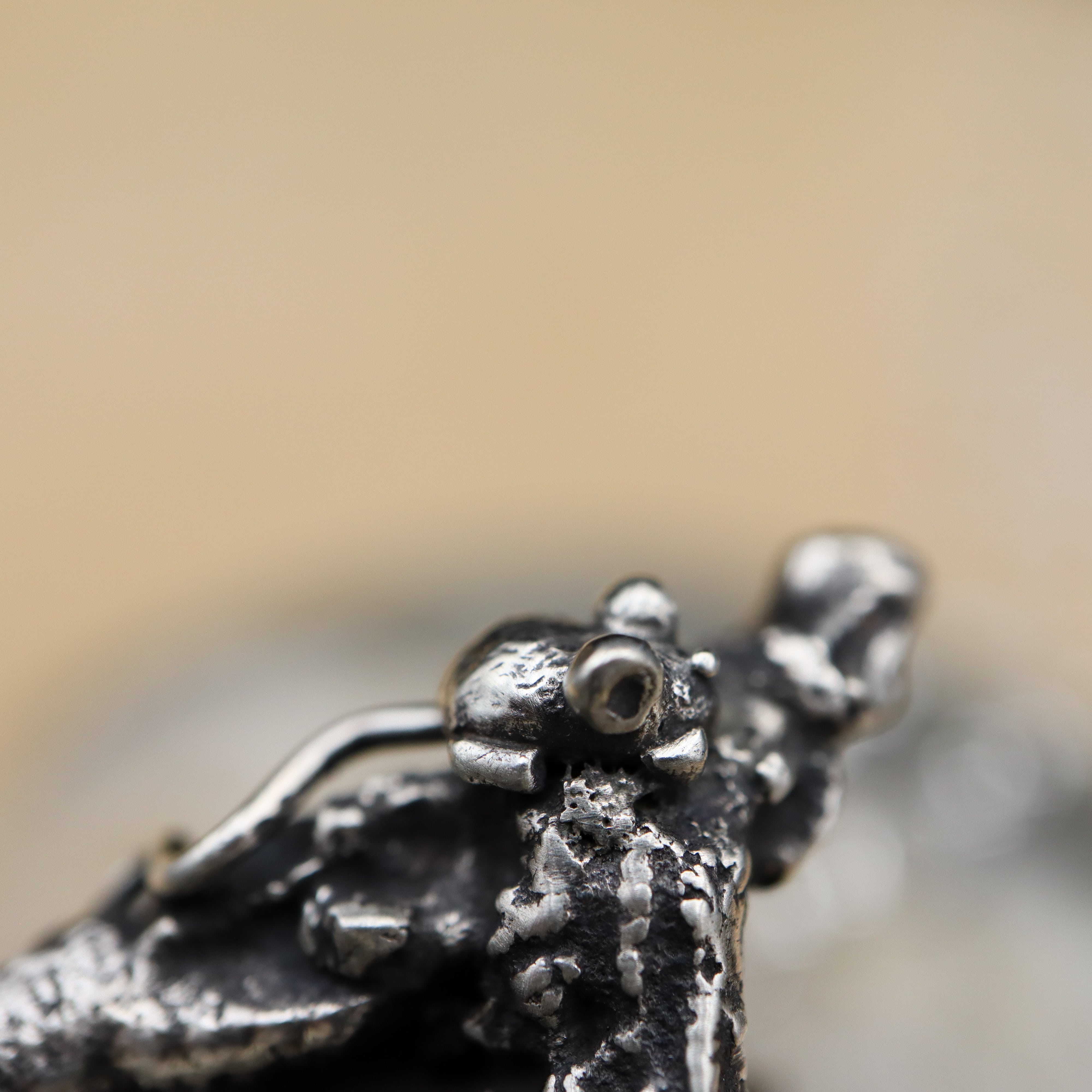 A close up photo of the tiny hand carved silver mouse at the top of the necklace.