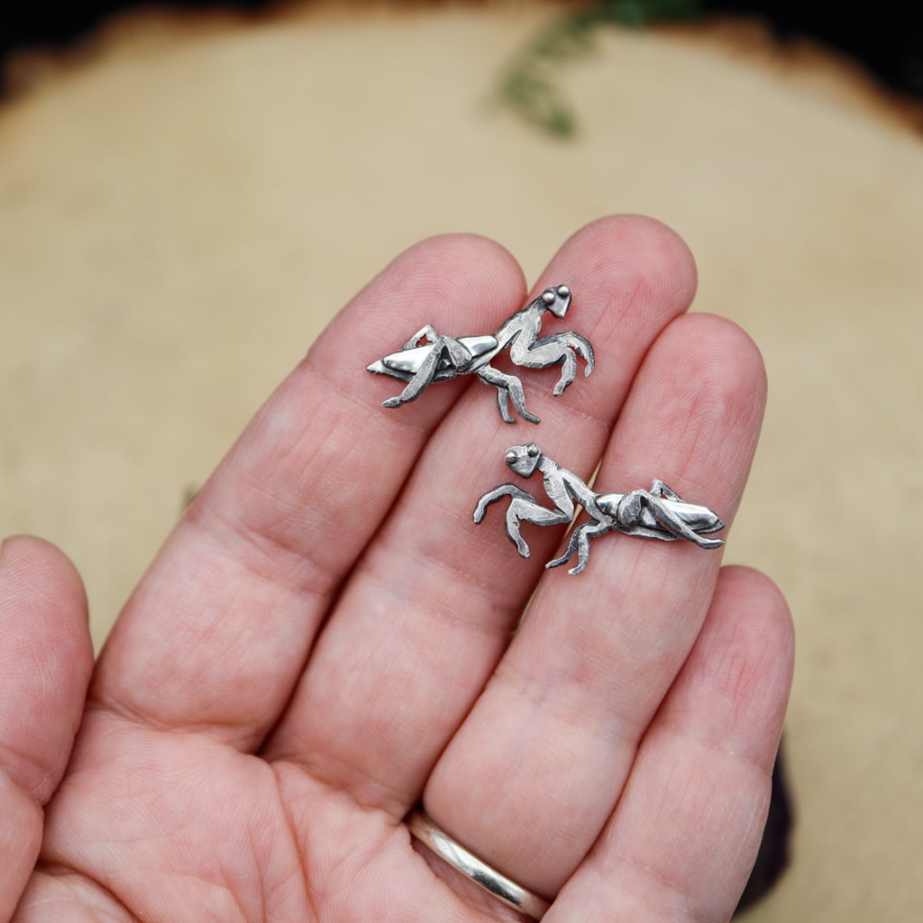 A hand is shown holding the sterling silver women's stud earrings showing that they are about 1 inch wide.