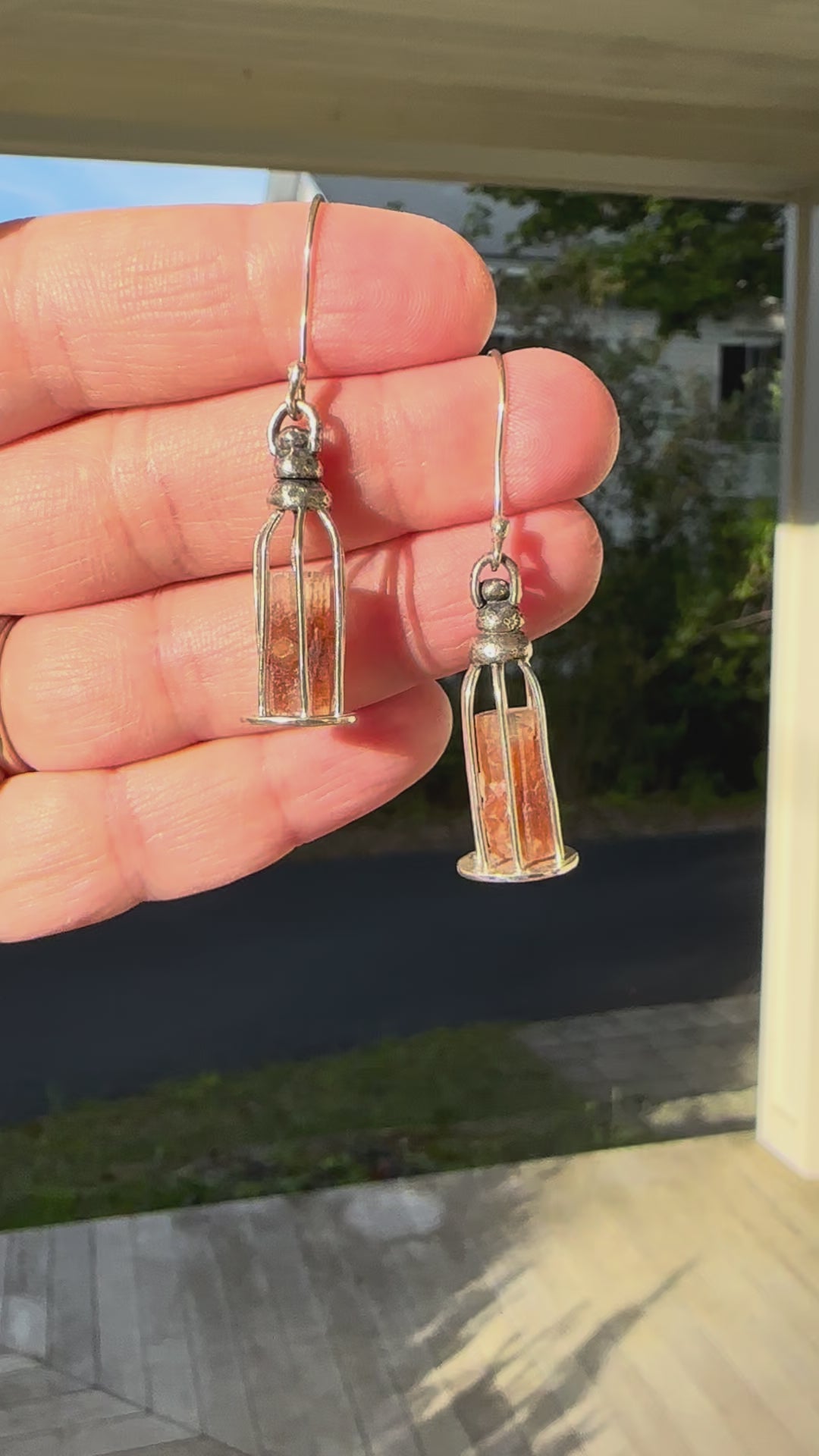 A video showing a hand holding the orange aragonite gemstone tower earrings.