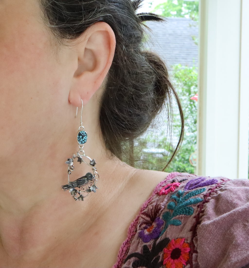 Robin and ivy earrings are shown being worn by a woman with dark brown hair. They are about 3 inches long and dangle.