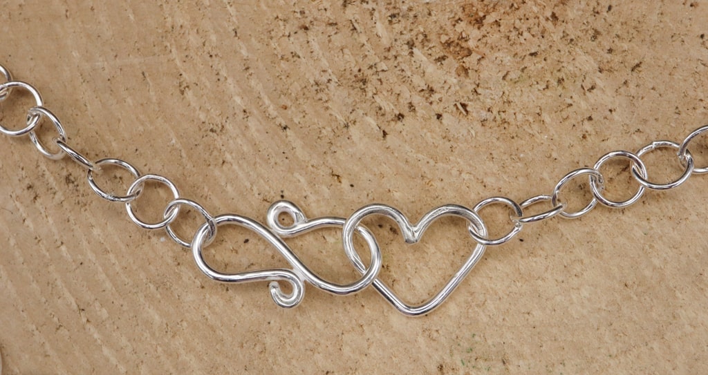 A necklace clasp consisting of a little heart and S clasp making the necklace adjustable.