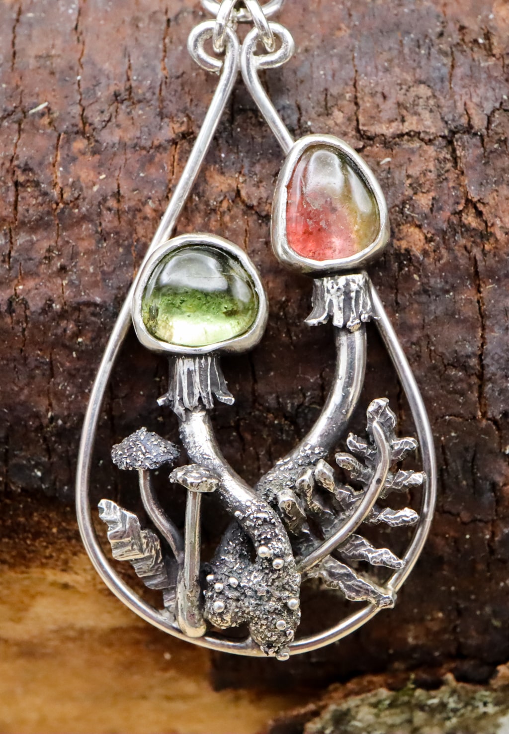 A close up of the other earring featuring two mushrooms. They are surrounded by ferns, mushrooms, and silver leaves as well.