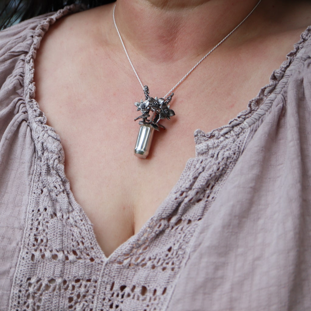 A woman is shown wearing the tiny sterling silver handmade trillium flower necklace.