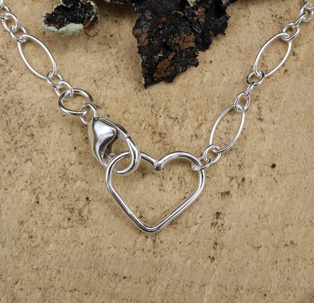 the claps of the necklace is made with a larger silver lobster claw on one side and a heart on the other to keep the necklace closed.