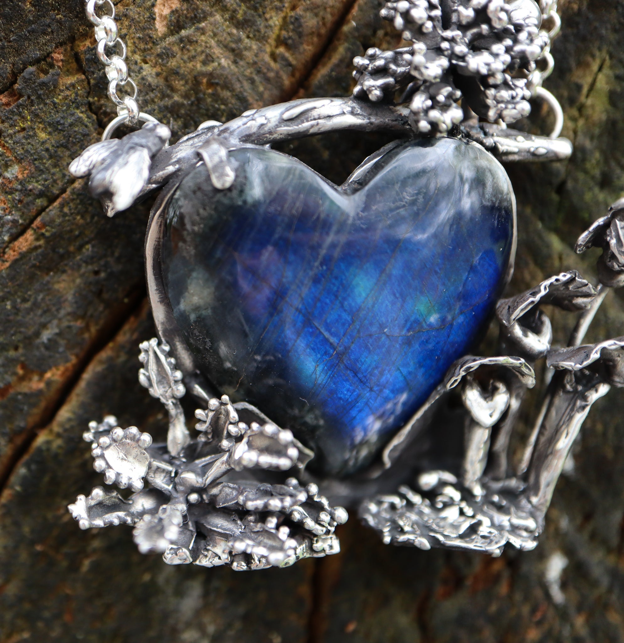 A close up of the left side of the pendant with the open venus fly trap and the little fly above the stone.