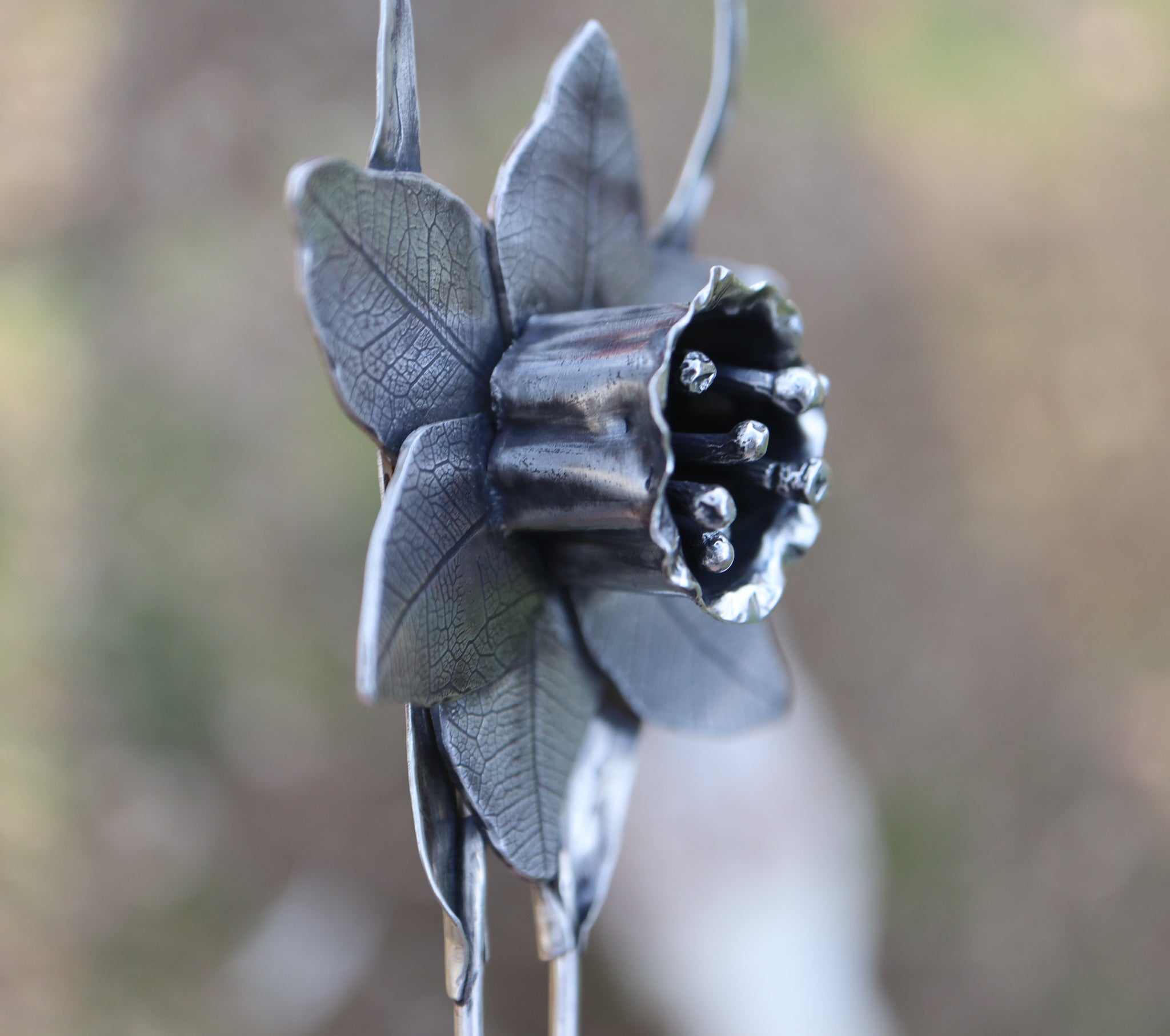The side view of the handmade daffodil hair pick showing the ruffles in the petals and leaf texture.