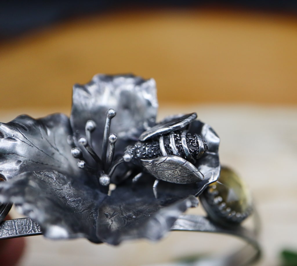 A top view of the tiny hand carved sterling silver honey bee in the center of the flower.
