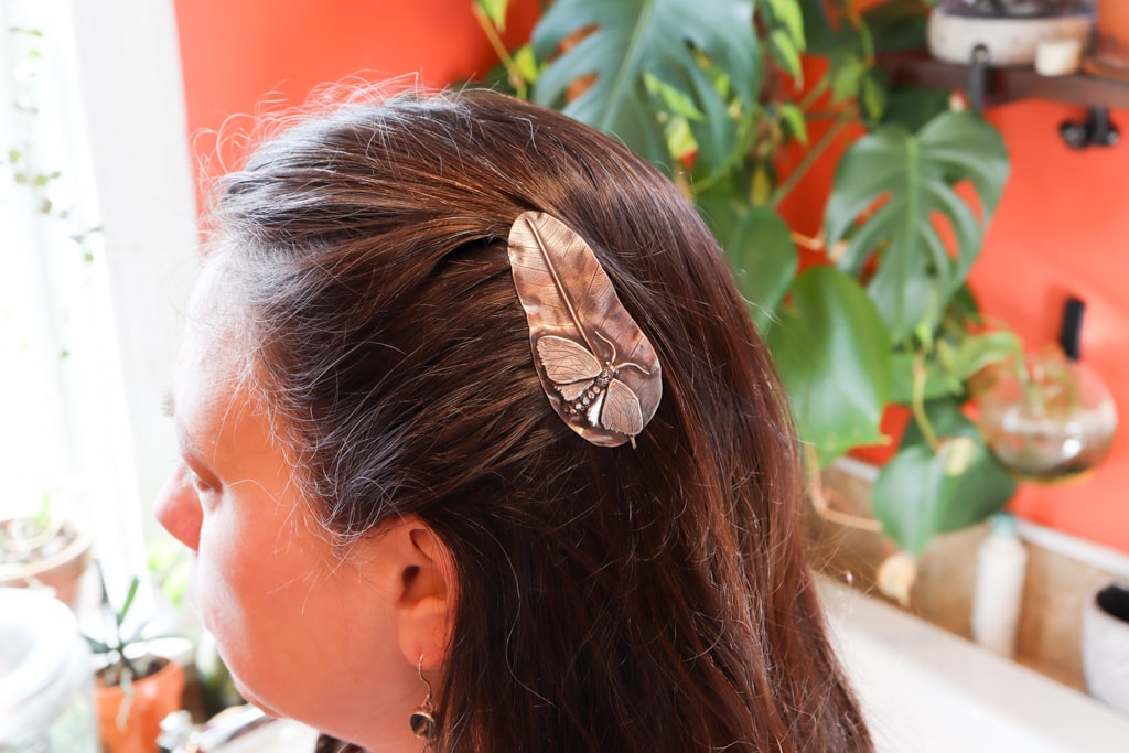 A sterling silver milkweed tussock moth hair comb being worn.