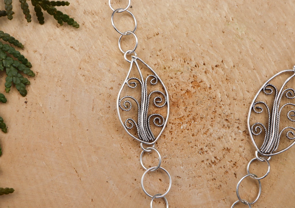 The handmade sterling silver leaves with filigree decoration that are within the necklace chain.