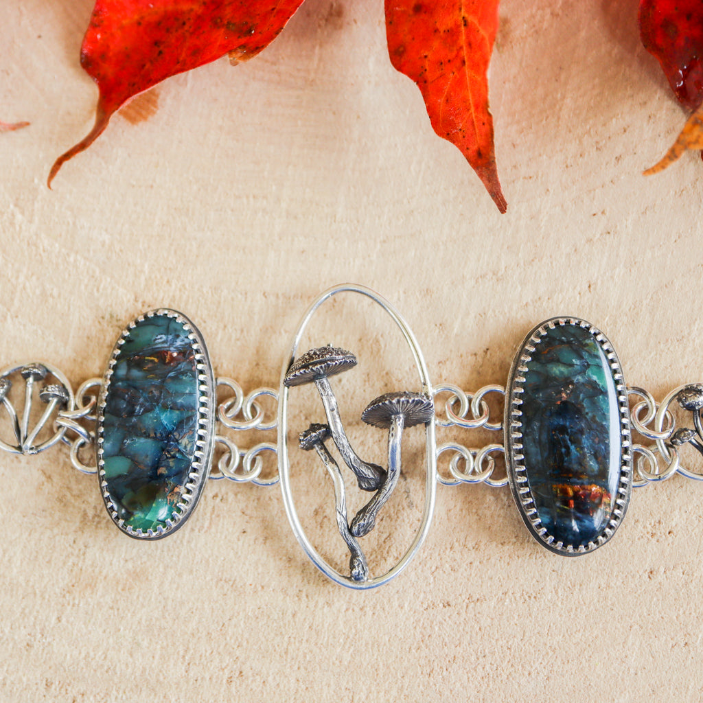 A handmade sterling silver mushroom bracelet with two opalized petrified wood cabochons on each side.