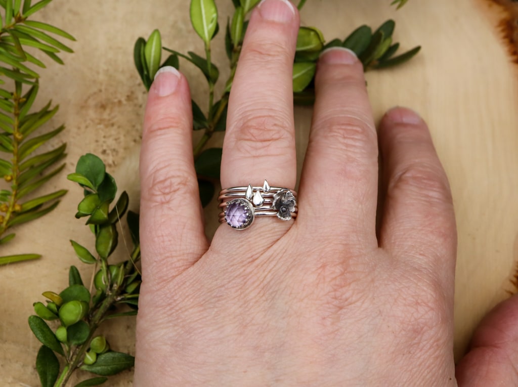 A hand is show wearing all five of the stacking rings together.