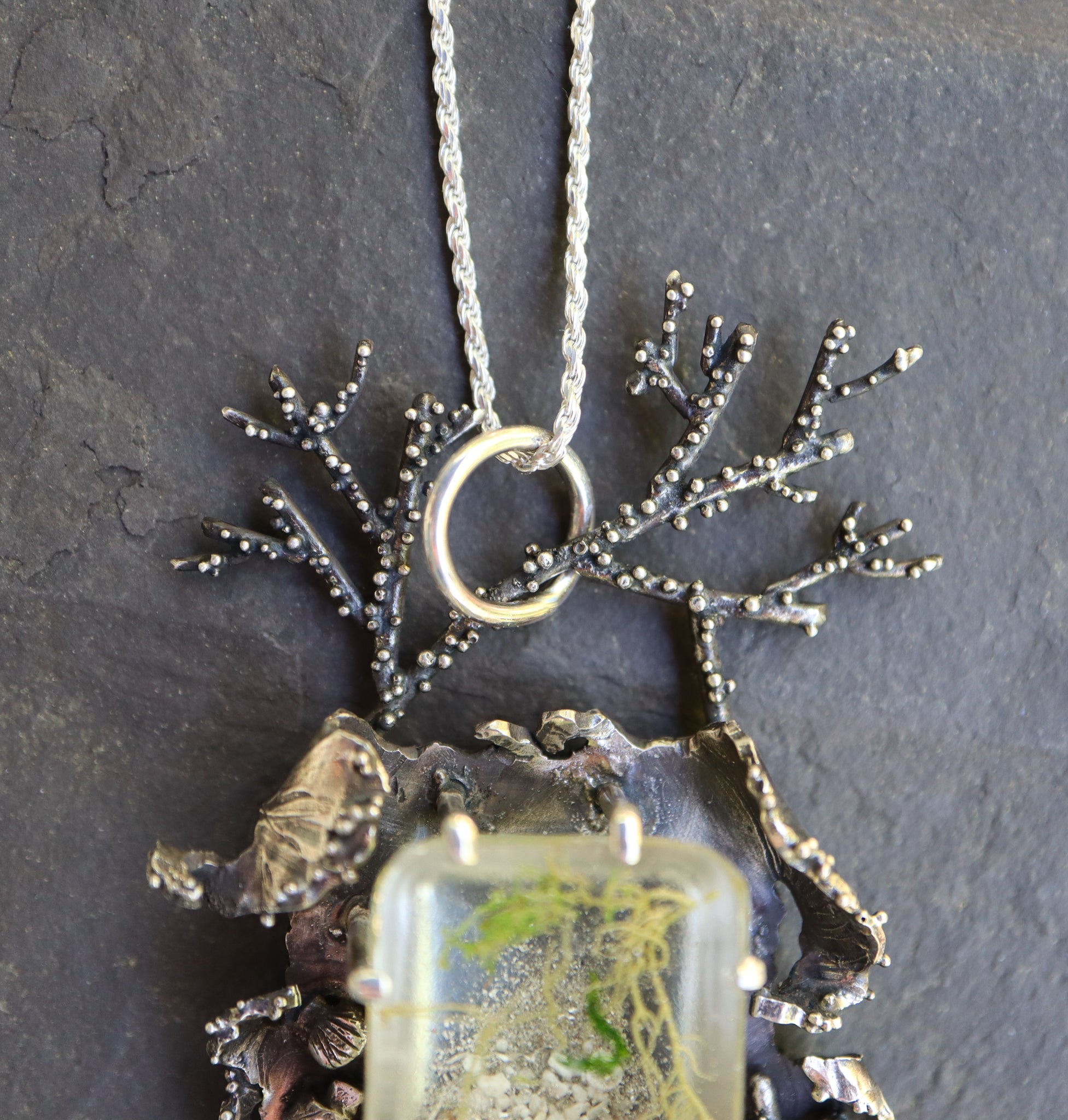 A branch coral is at the top of the pendant with lots of texture. It is made to hold the pendant on it's necklace.