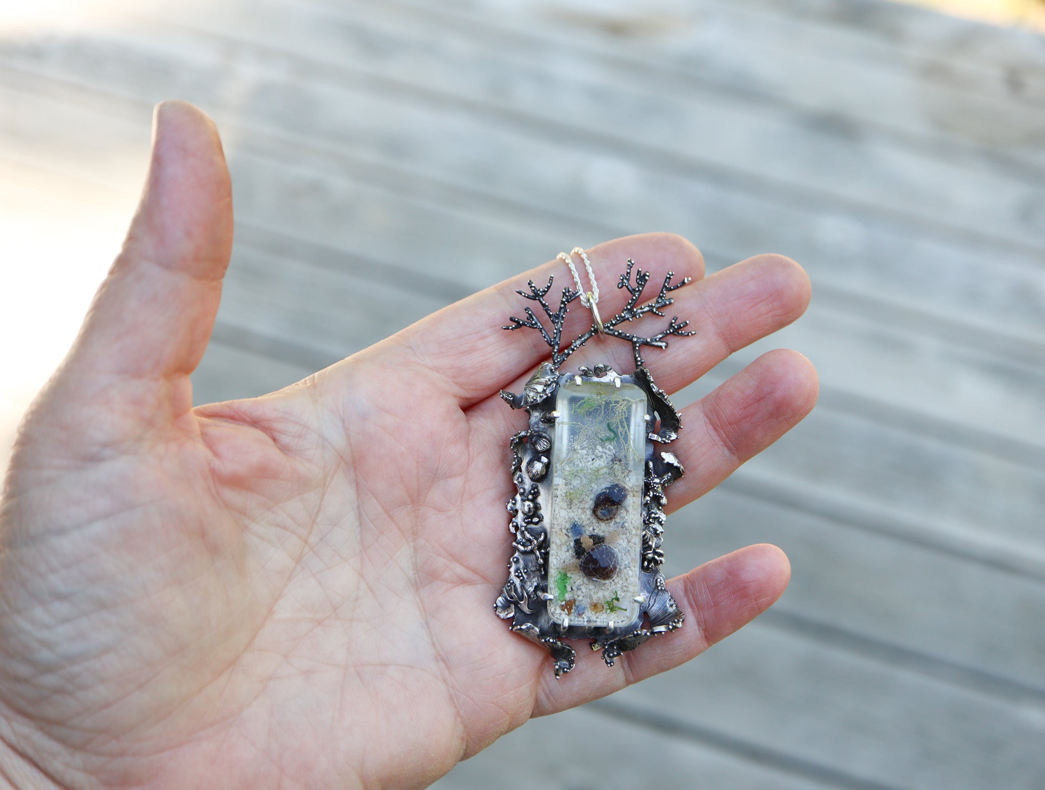 A hand is shown holding the pendant for size reference. It is about 3 inches tall and 1.5 inches wide. .