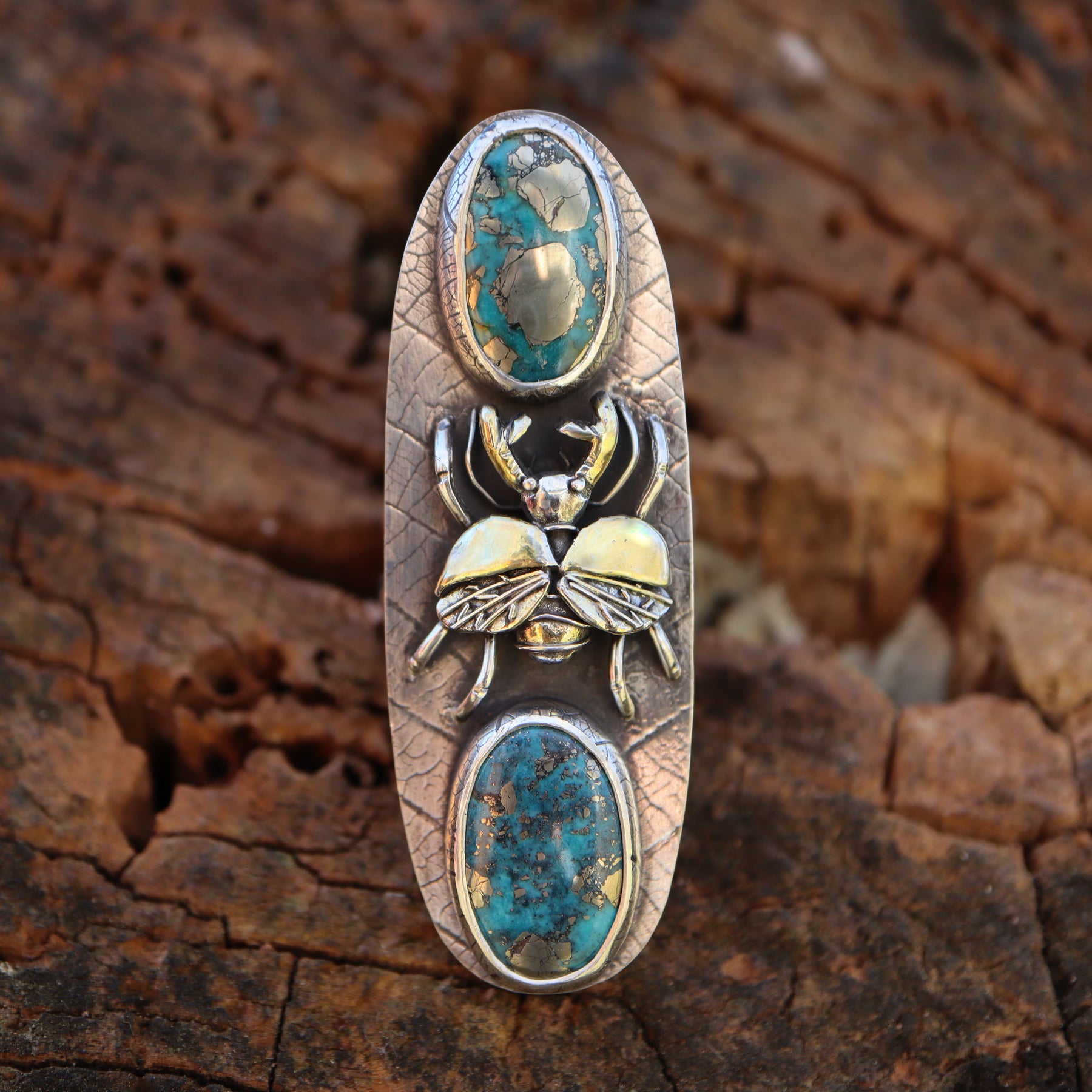 Sterling silver and 24 karat gold stag beetle ring with two morenci turquoise stones with flecks of silver pyrite in them. The background of the ring is pressed with a real leaf and is about 2 inches tall.
