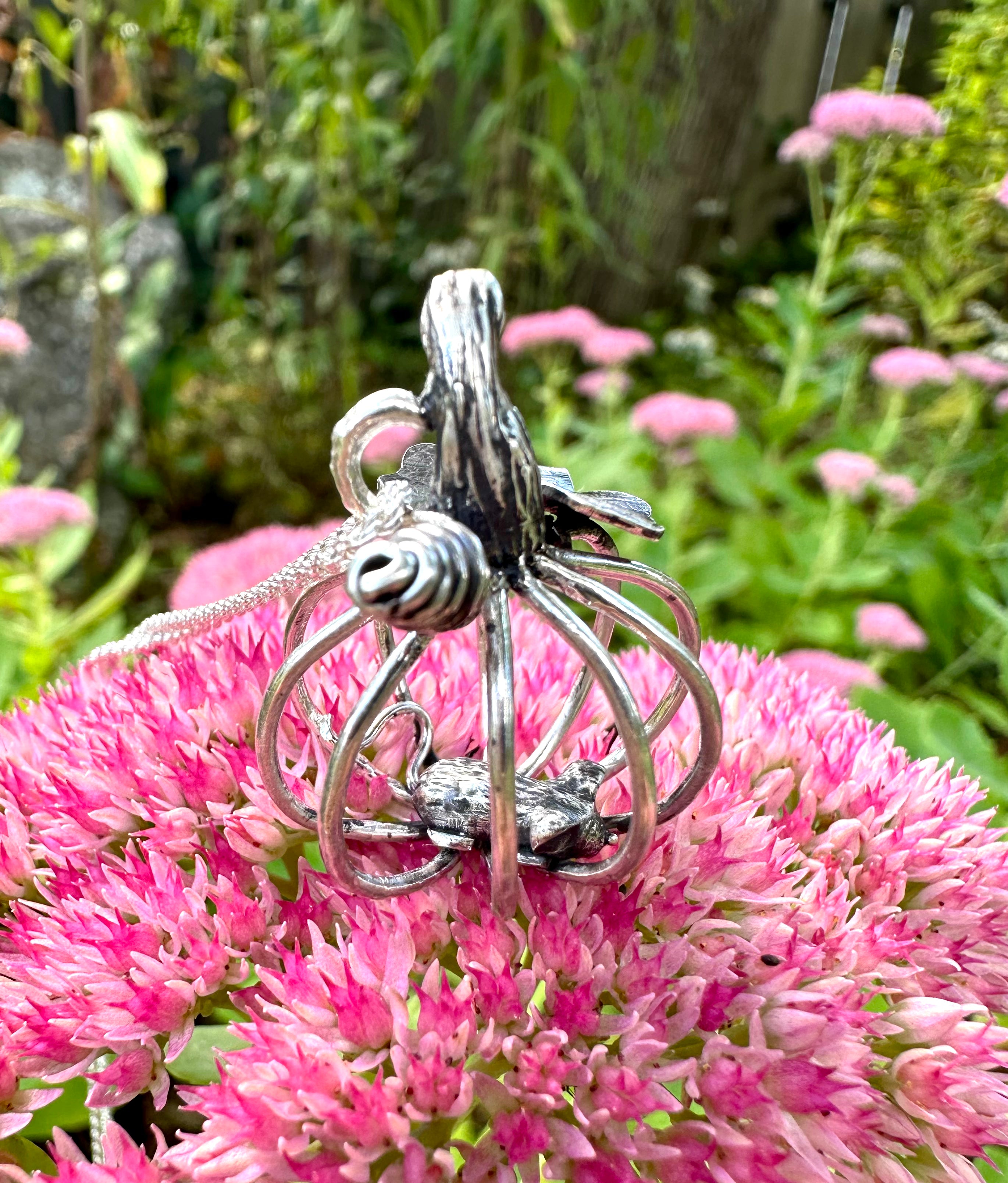 Silver pumpkin and mouse pendant on pink flowers with a garden background