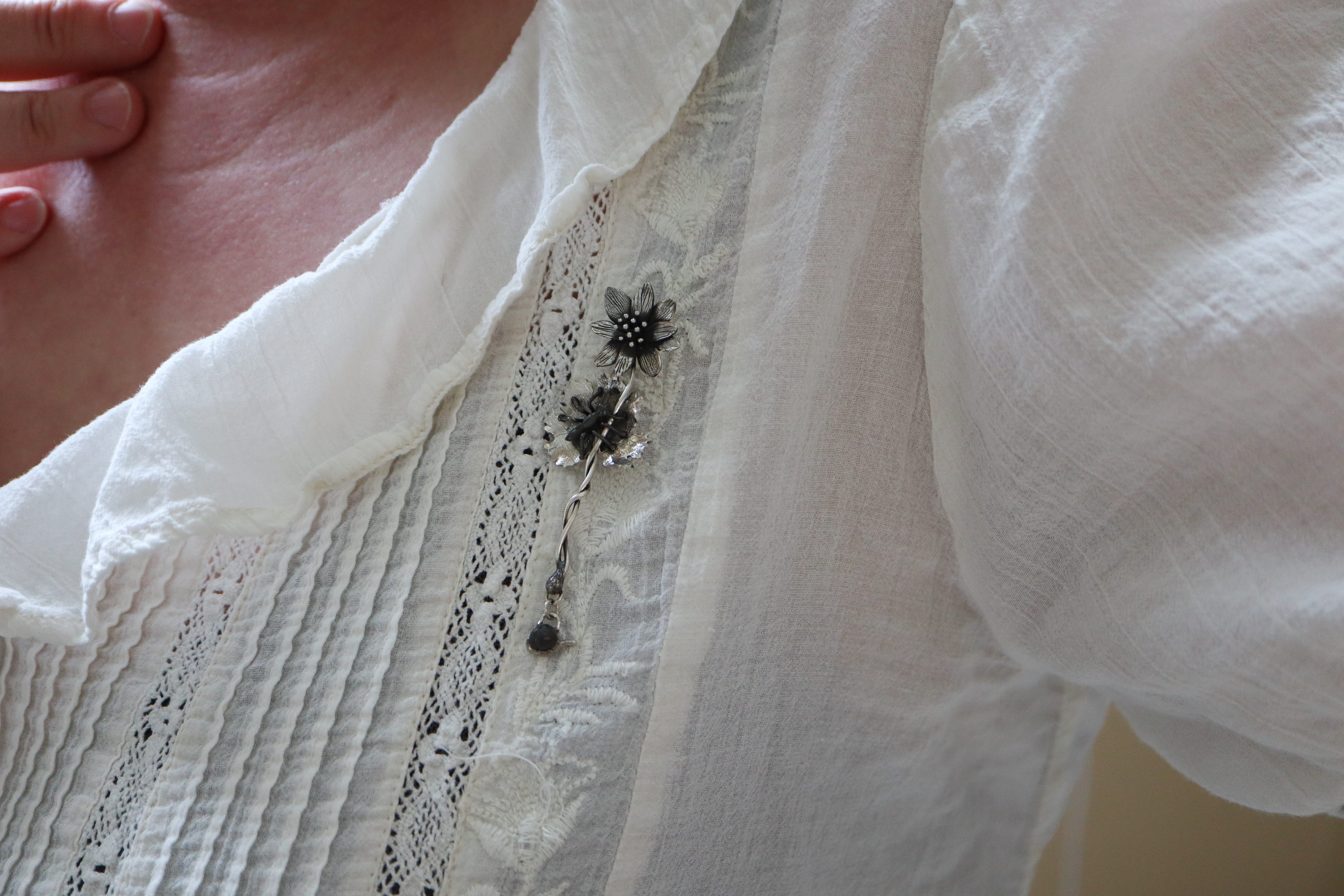 The bloodroot flower brooch is shown being worn on a bright white blouse.