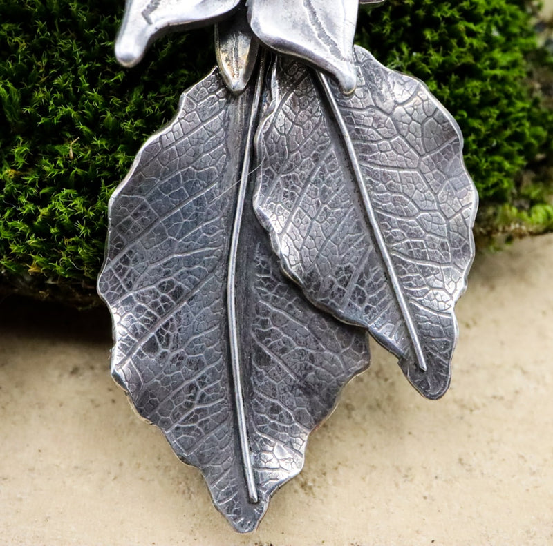 A close up photo of the sterling silver leaves that dangle below the borage flowers. 
