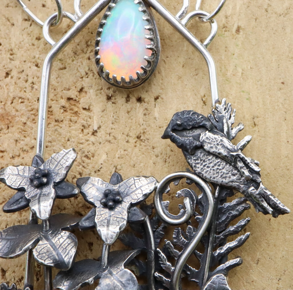 A close up of the sterling silver chickadee bird and part of the opal gemstone. 