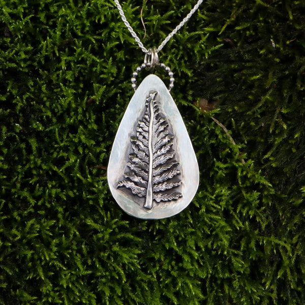 Sterling silver fern necklace. The pendant is about 2 inches tall and on an 18 inch long sterling silver necklace. One of a kind silver fern jewelry shown on a clump of dark green moss. 
