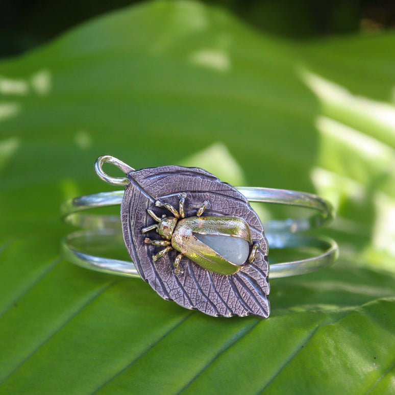 A glow in the dark firefly bracelet is shown on a light green lead outdoors in dappled sun. 