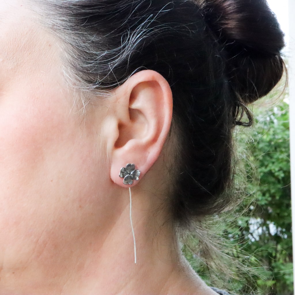 A woman with her dark hair up in a bun is shown wearing the 4 leaf clover earrings.