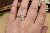 A hand is shown wearing the tiny silver ghost ring. 