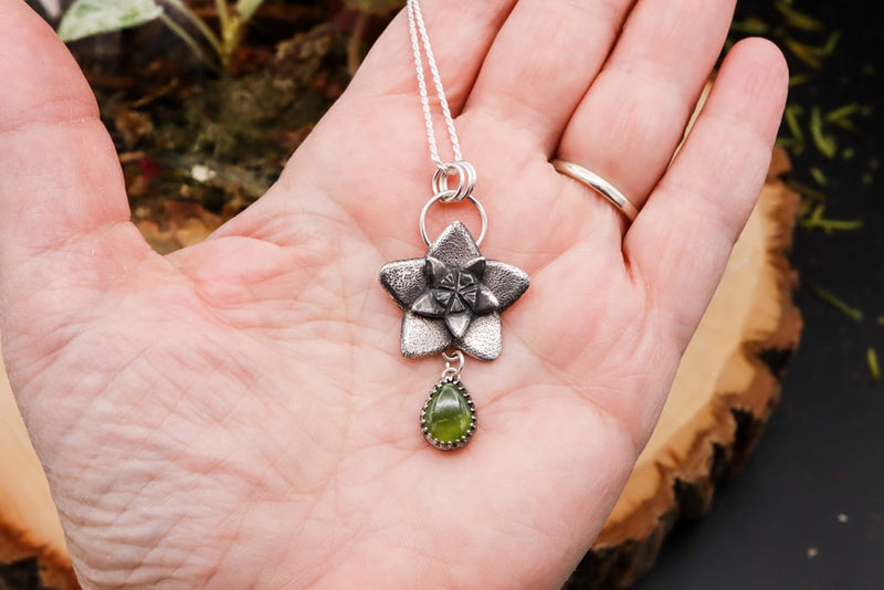 A hand is shown holding the hoya flower necklace to show size reference. The pendant is about 2 inches tall.