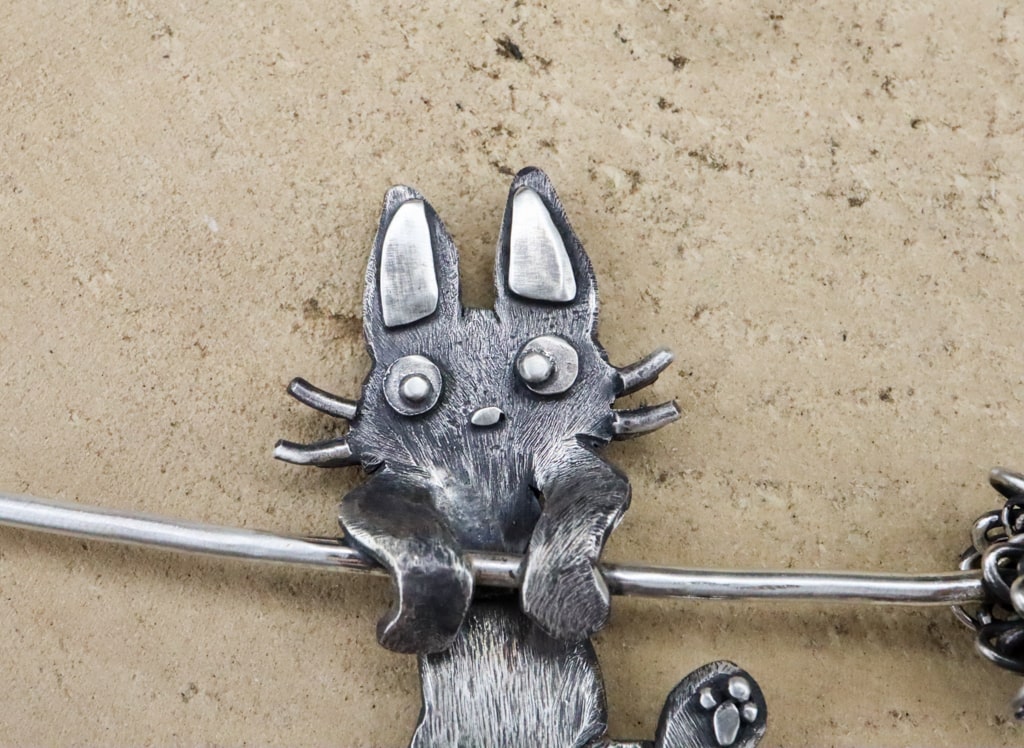 A close up of the Jiji cat necklace face. 