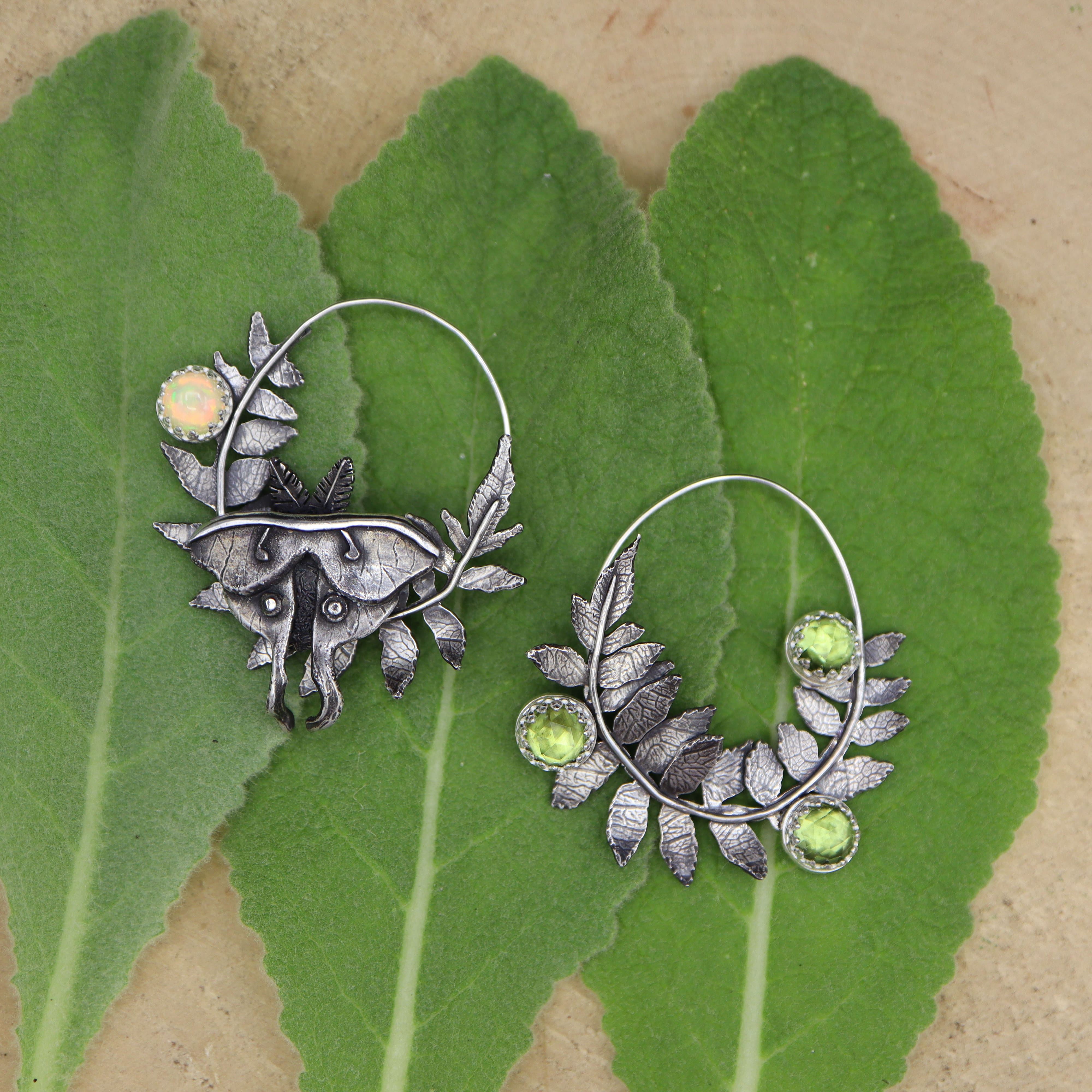 Silver luna moth and staghorn sumac branch earrings with green peridot stones  and opal on green leaves