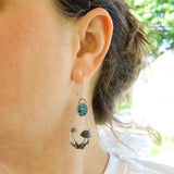A woman is shown wearing the mushroom earrings. They dangle from her ear and are about 2 inches long. 