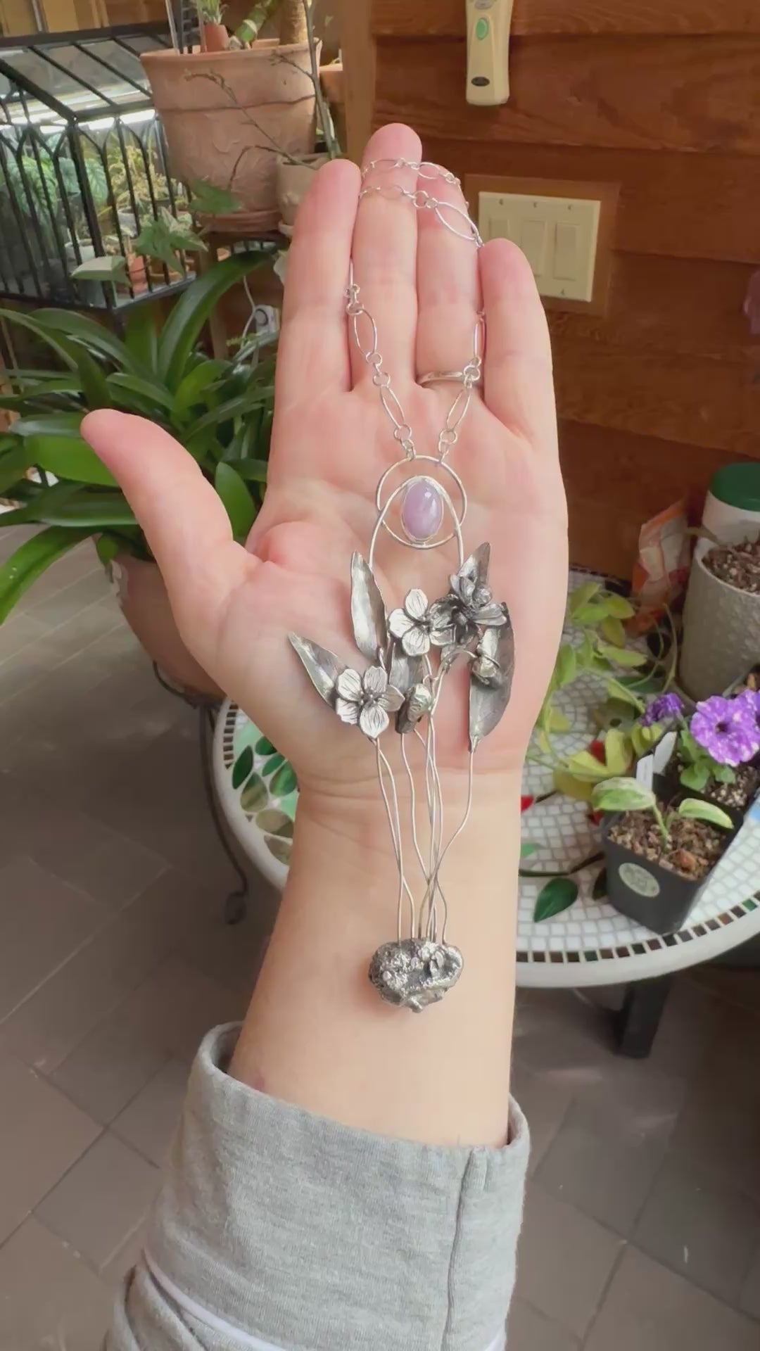 A video showing a hand holding the spring beauty wildflower necklace at different angles. 