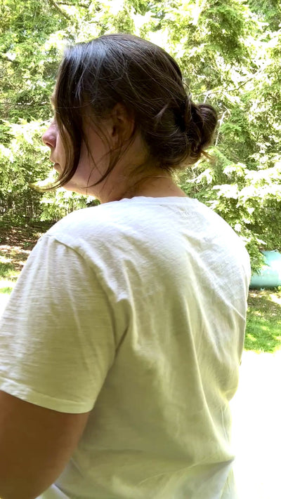The hair comb is being shown worn by a woman with twisted up dark hair while outdoors. 