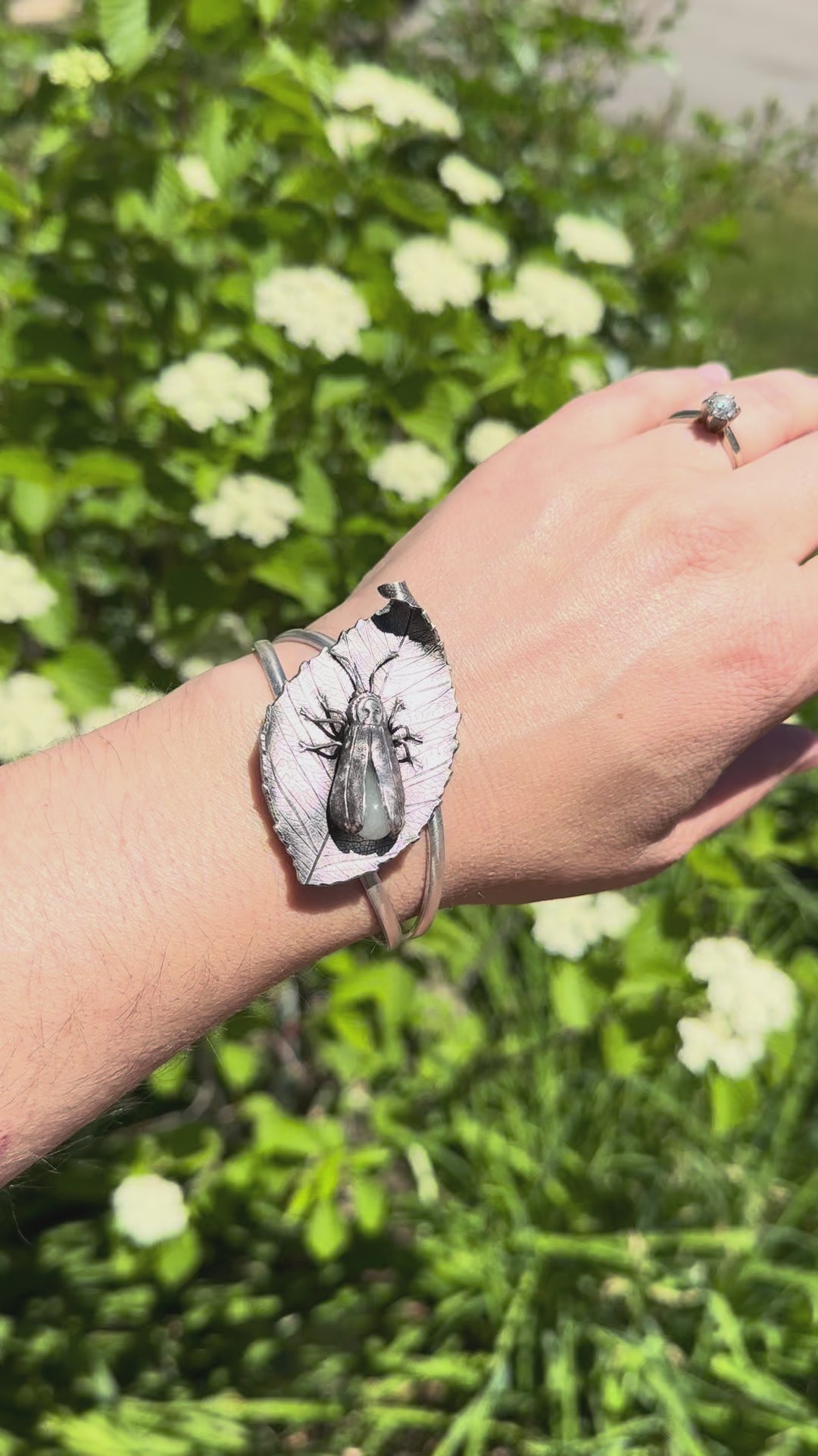 A video showing the glow in the dark sterling silver firefly bracelet being worn on a wrist. The woman wears it outdoors in the sunshine and then goes indoors with it to show the glow from the glass abdomen. 