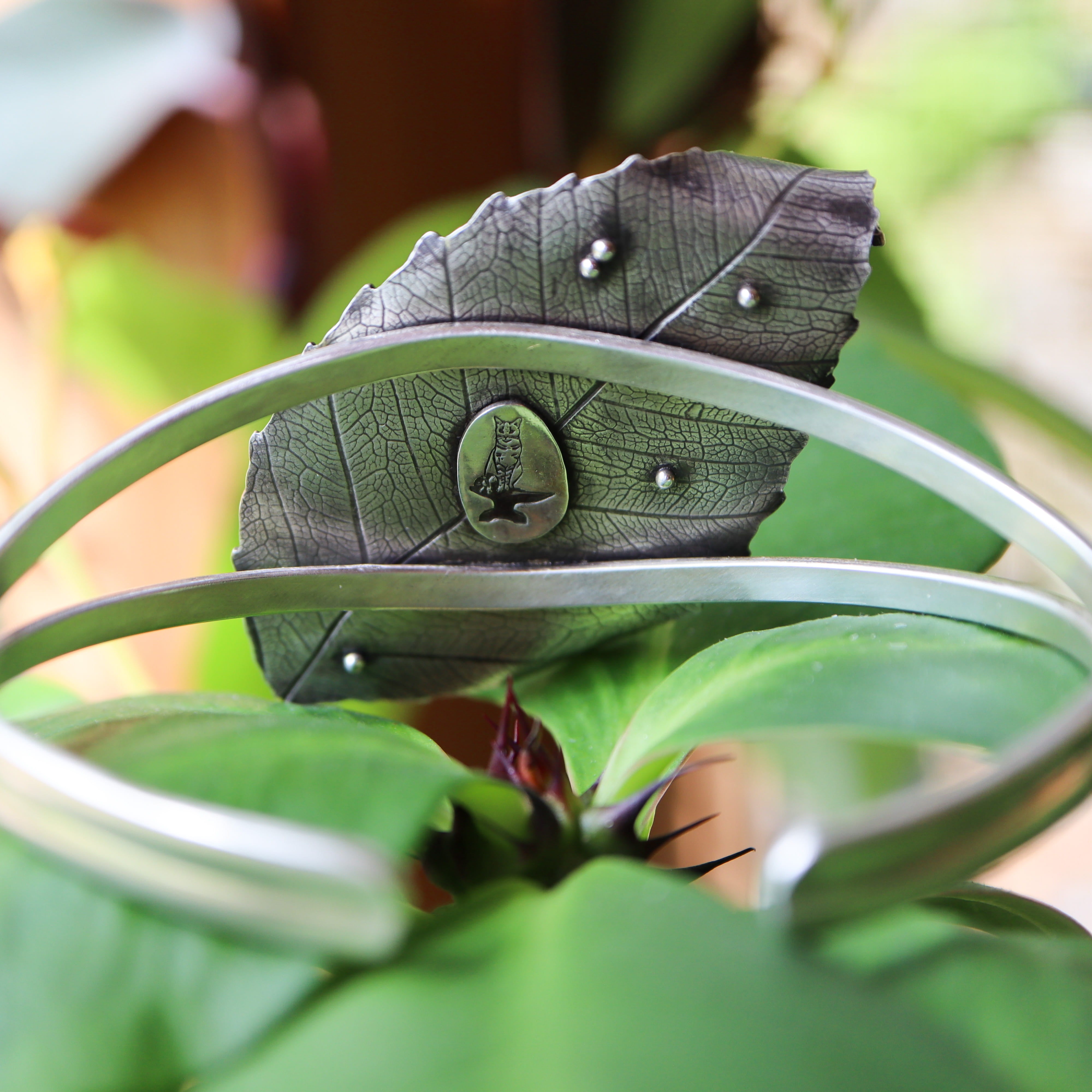 The back of the handmade bracelet showing 5 small silver "eggs" hidden and The Striped Cat Metalwork's maker mark. 