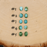 There are five different pairs of mismatched stones that you can choose from all about the same size. They are shown on a piece of light tan wood. 