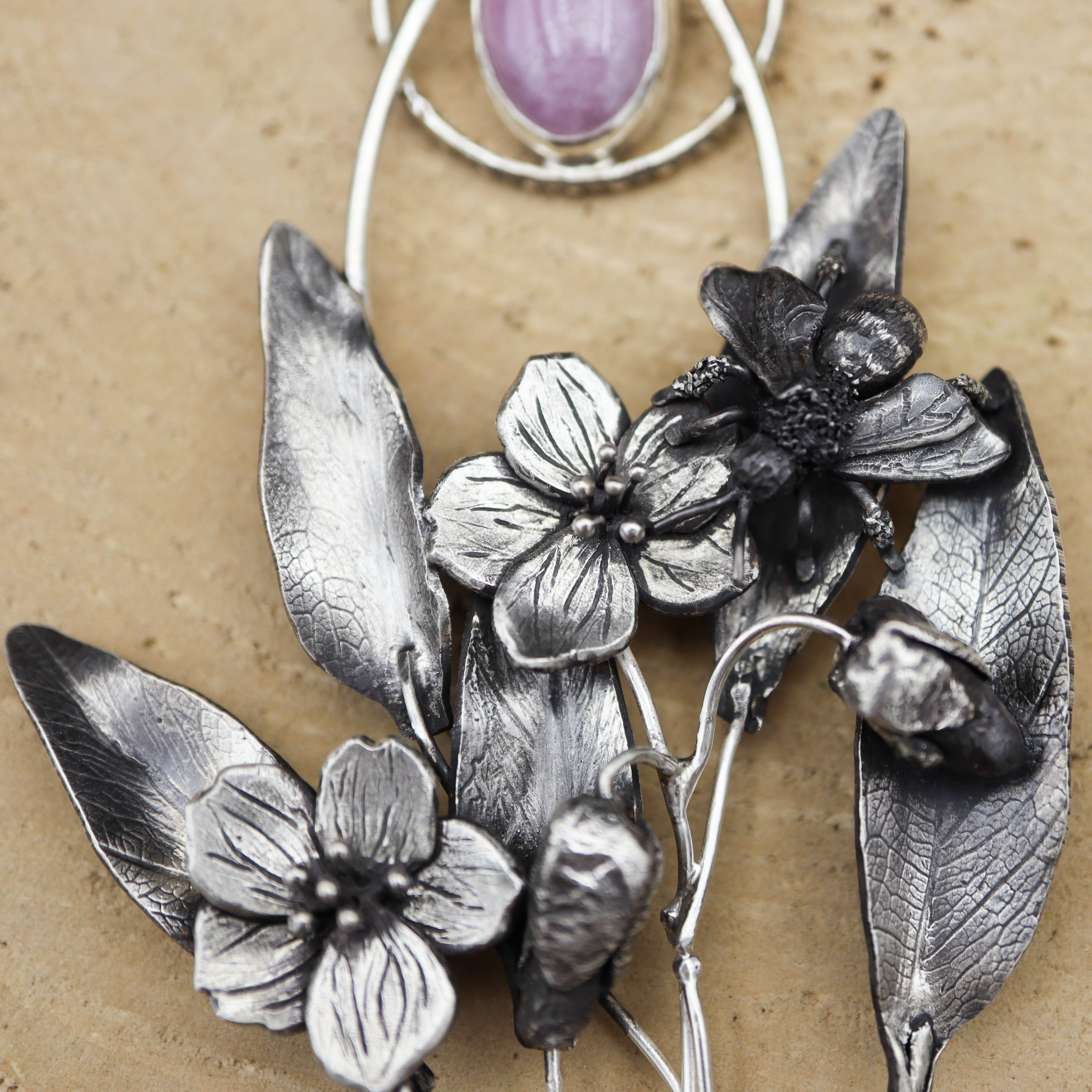 A close up of a spring beauty mining bee that is part of a sterling silver wildflower necklace. 