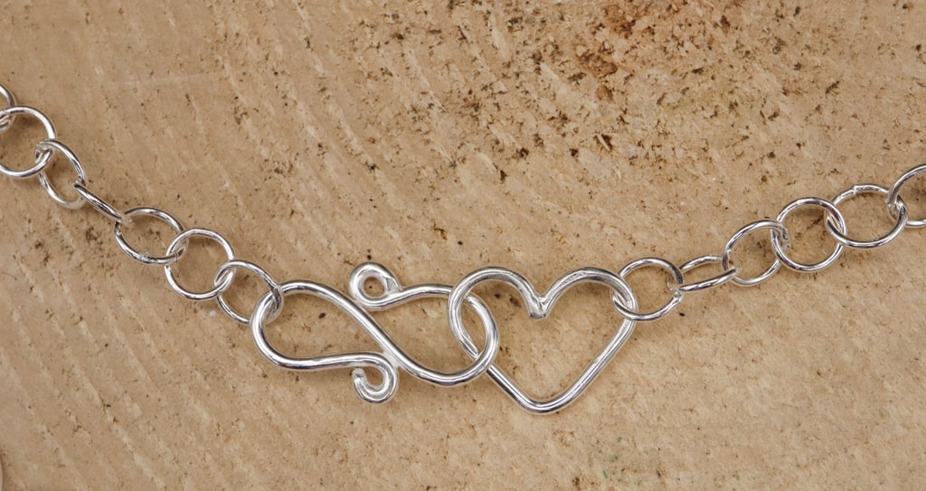 A necklace clasp consisting of a little heart and S clasp making the necklace adjustable. 