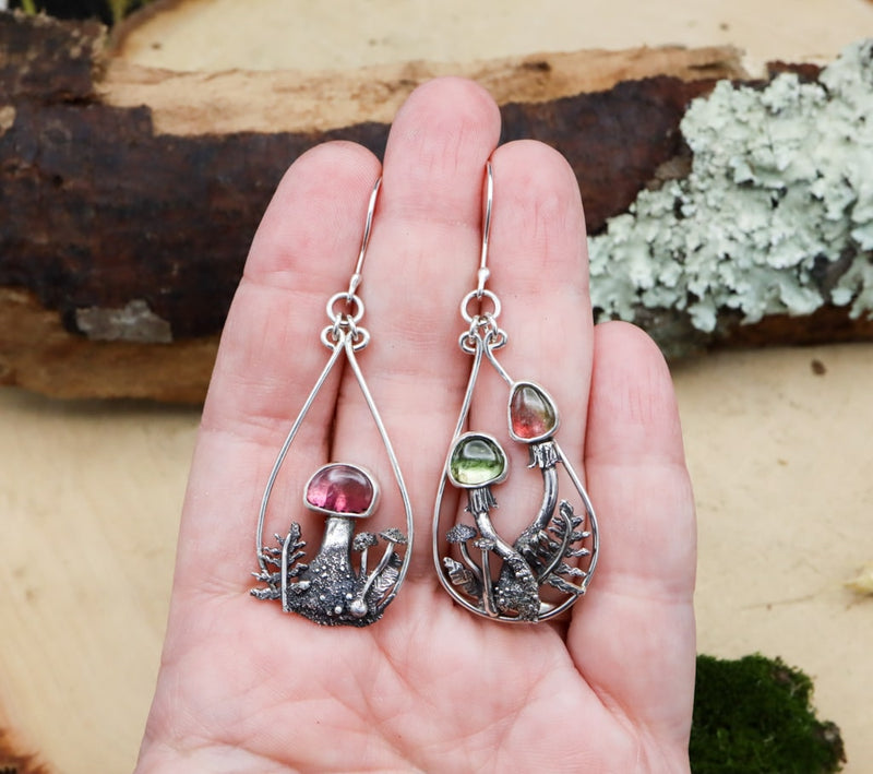 A hand is shown holding the pair of earrings showing that they are about 3 inches long. 