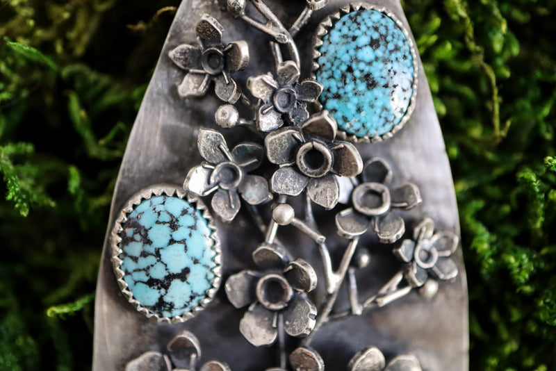 Another close up view of the sprig of forget-me-not flowers and two of the turquoise stones. 